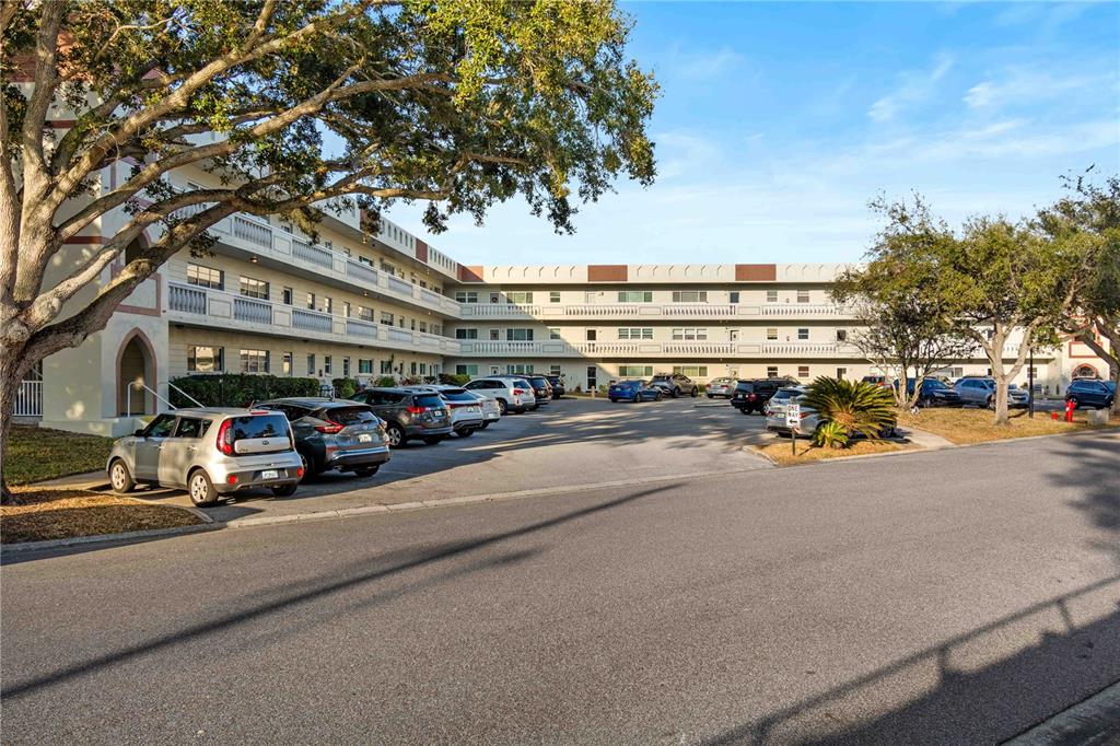 A multi-story apartment building with a parking lot in front under a large tree — 2284 SPANISH DRIVE UNIT 50, CLEARWATER, FL