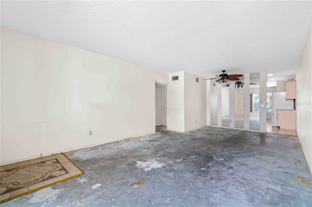 An empty living room features a concrete subfloor, mirrored wall panels, and a ceiling fan — 2284 SPANISH DRIVE UNIT 50, CLEARWATER, FL