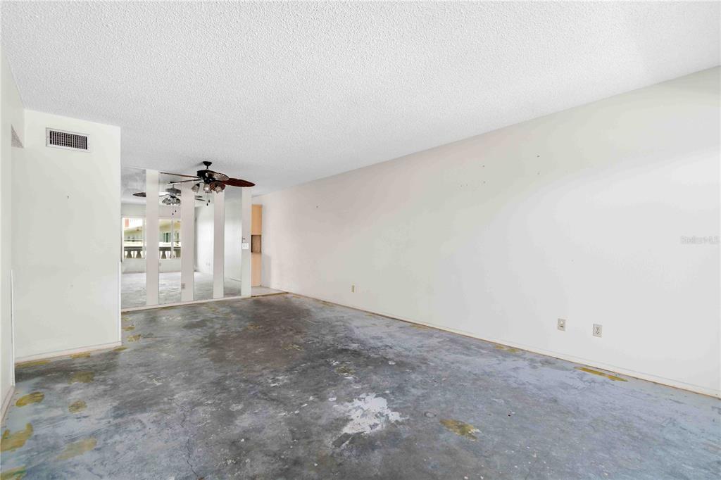 An empty room with a popcorn ceiling, bare concrete floors, and a mirrored wall — 2284 SPANISH DRIVE UNIT 50, CLEARWATER, FL