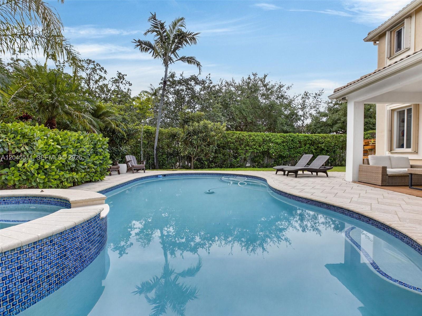A backyard features a swimming pool, a hot tub, lounge chairs, and a covered patio — 1401 Canary Island Dr, Weston FL 33327, WESTON, FL