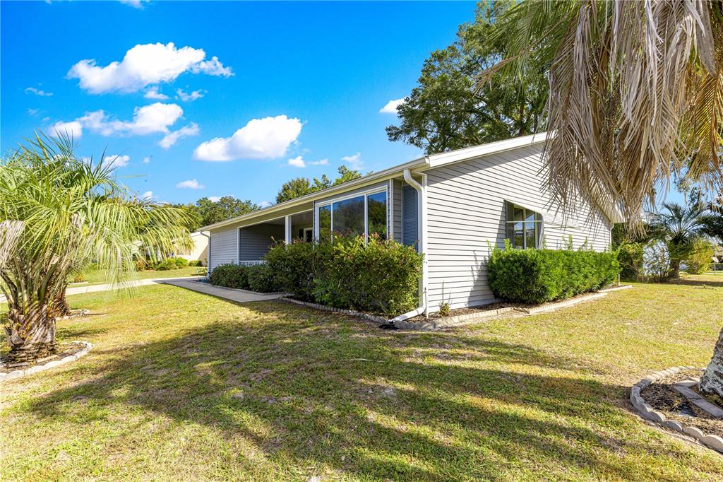 A single-story house with light gray siding, a covered porch, and surrounding landscaping — 10987 SW 86TH TERRACE, OCALA, FL