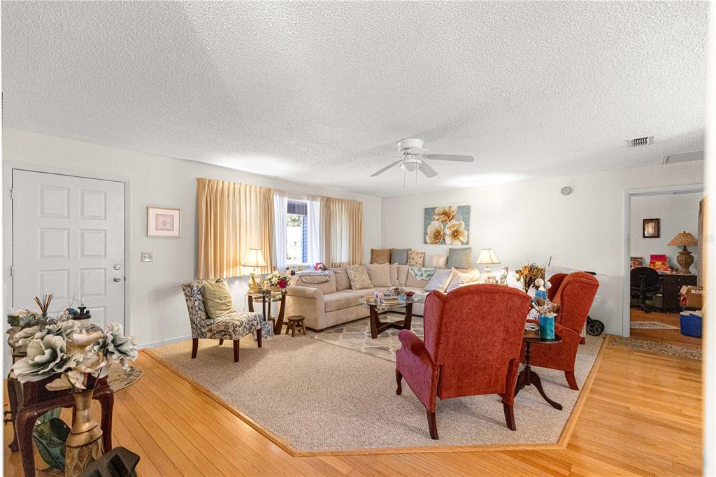 A living room features a beige sectional, two red armchairs, hardwood floors, and a ceiling fan — 10987 SW 86TH TERRACE, OCALA, FL