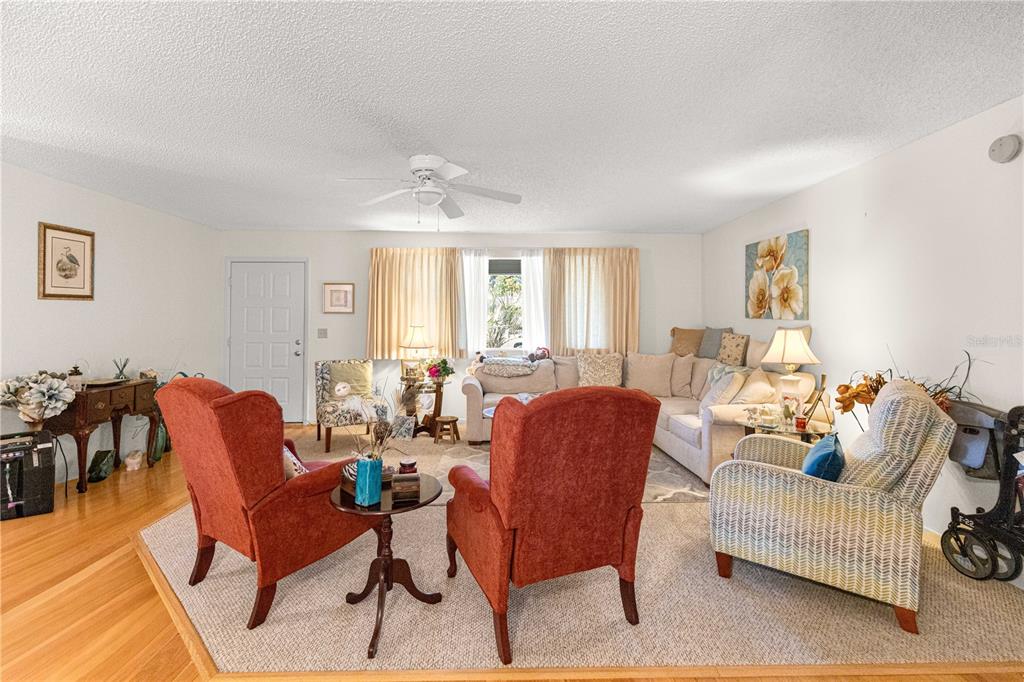 A living room features hardwood floors, a large sectional sofa, and two red armchairs — 10987 SW 86TH TERRACE, OCALA, FL