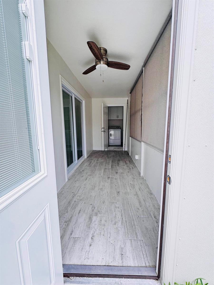 A narrow, covered porch with wood-look tile flooring leads to a laundry room doorway — 293 Flanders G, Delray Beach FL 33484, DELRAY BEACH, FL