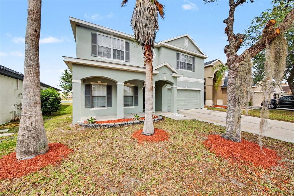 A two-story house with a light green exterior, a front porch, and a two-car garage — 2512 HOLLY PINE CIRCLE, ORLANDO, FL