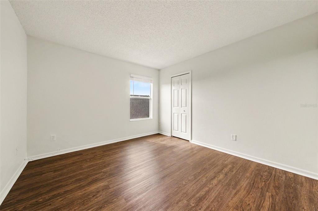 An empty bedroom features light-colored walls, a single window, and dark wood-look flooring — 2512 HOLLY PINE CIRCLE, ORLANDO, FL