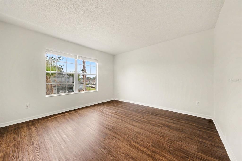 An empty bedroom features white walls, a single window, and dark wood-look flooring — 2512 HOLLY PINE CIRCLE, ORLANDO, FL