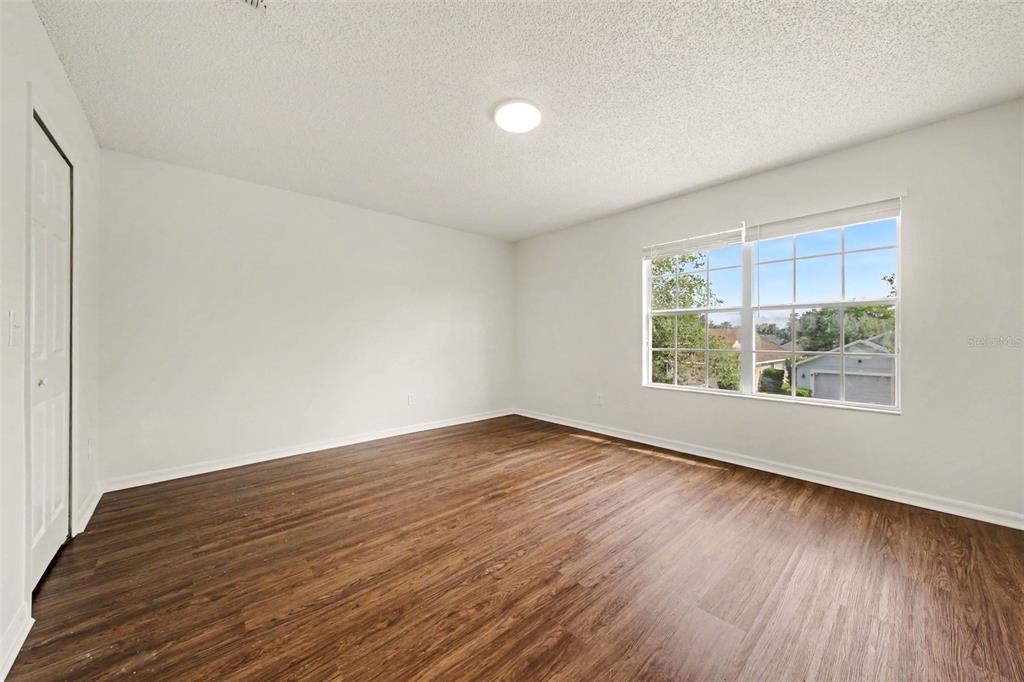 An empty bedroom features white walls, wood-look flooring, a ceiling light, and a window — 2512 HOLLY PINE CIRCLE, ORLANDO, FL