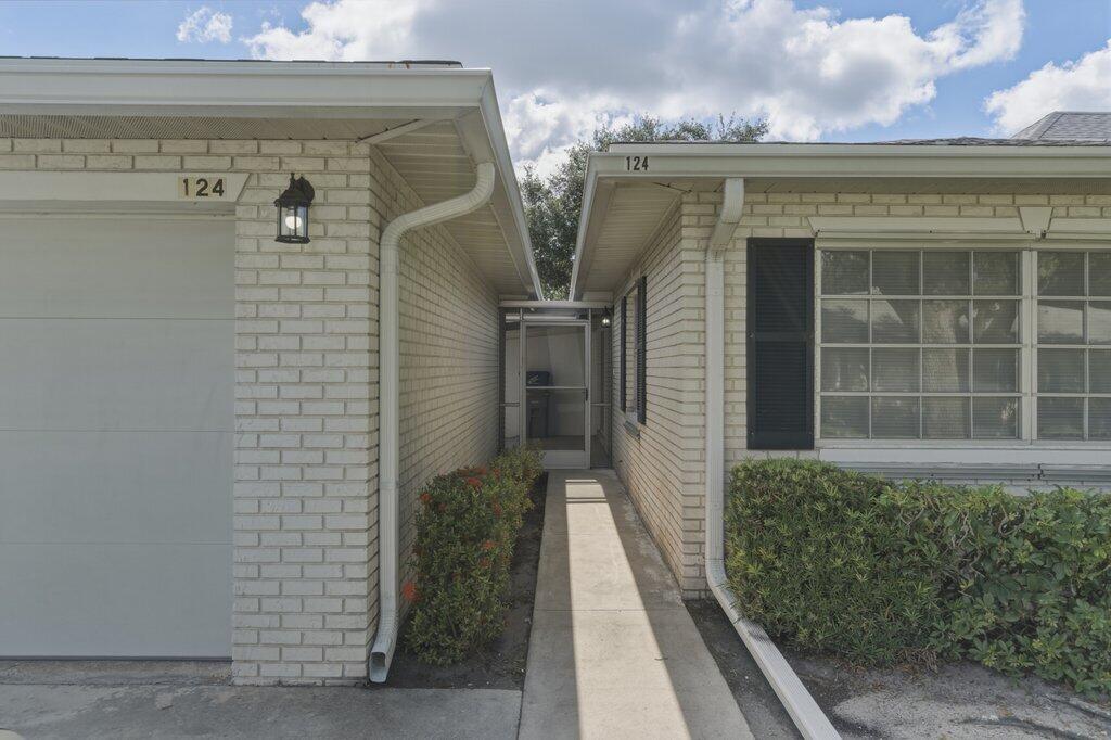 A concrete walkway leads to a screened front entryway between two light-colored brick building sections — 10098 S 42nd Drive, Boynton Beach FL 33436, BOYNTON BEACH, FL