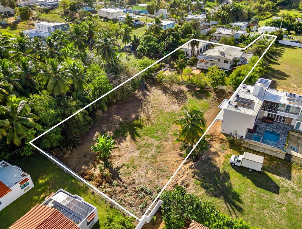 An aerial view shows a rectangular vacant lot bordered by a white line near houses — KM 1.1 466, ISABELA, PR