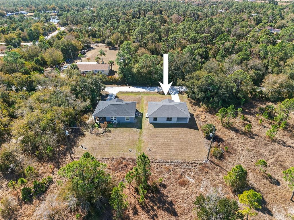 An aerial view shows two adjacent single-family homes surrounded by a wooded landscape — 27130 SAVOY DRIVE, PUNTA GORDA, FL
