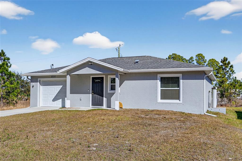 A single-story gray house with a garage and a front porch under a blue sky — 27130 SAVOY DRIVE, PUNTA GORDA, FL