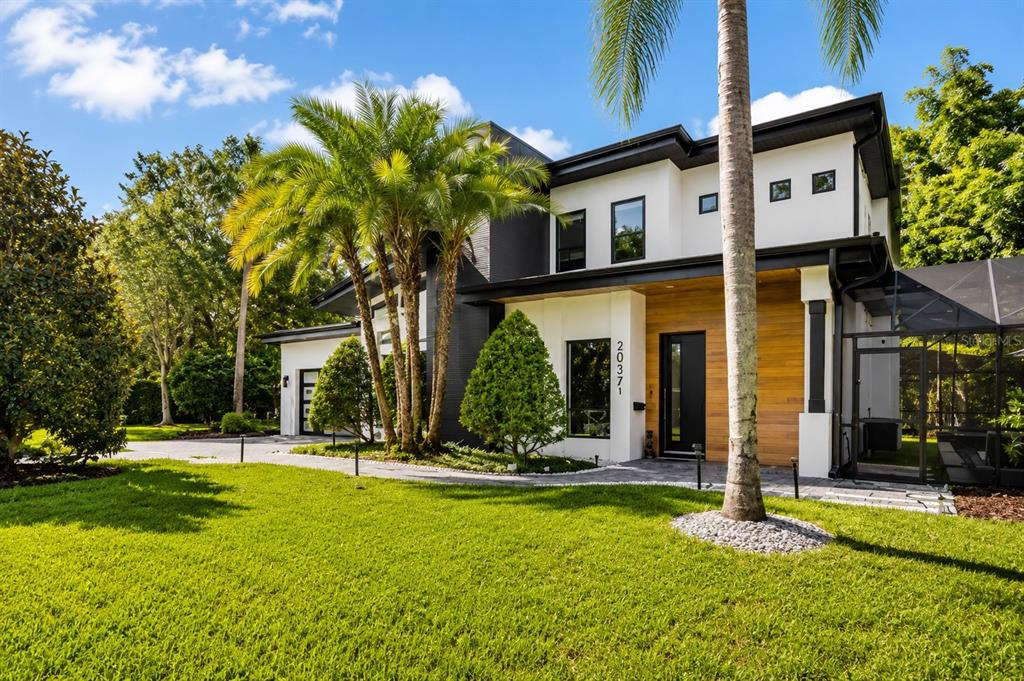 A modern two-story house with white and dark gray exterior walls, wood accents, and palm trees — 2032 KIMBRACE PLACE, WINTER PARK, FL