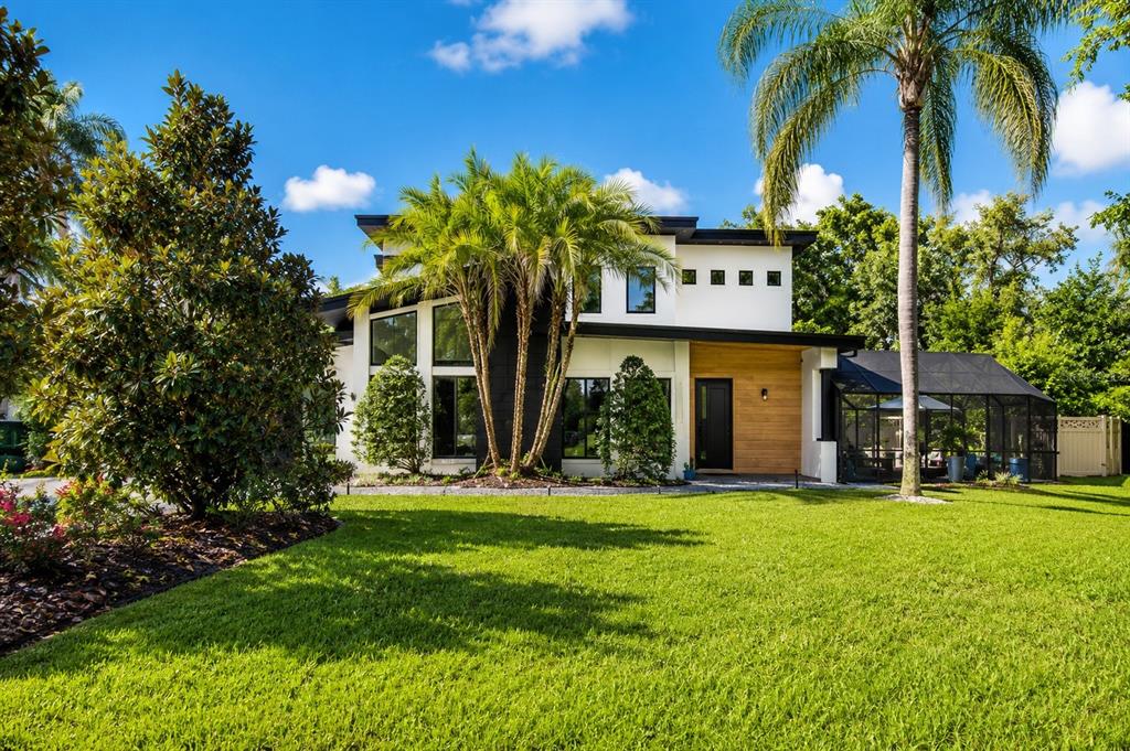 A modern two-story house with white and black exterior walls, wood accents, and palm trees — 2032 KIMBRACE PLACE, WINTER PARK, FL