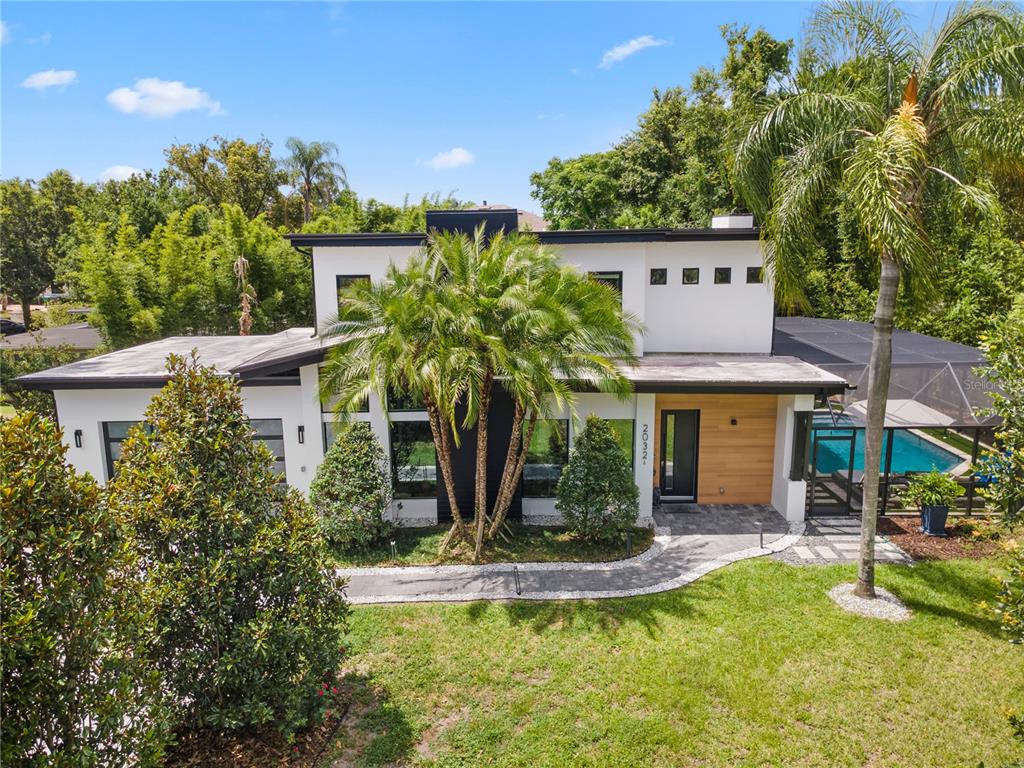 A modern two-story house features white stucco walls, wood accents, and a palm tree landscape — 2032 KIMBRACE PLACE, WINTER PARK, FL