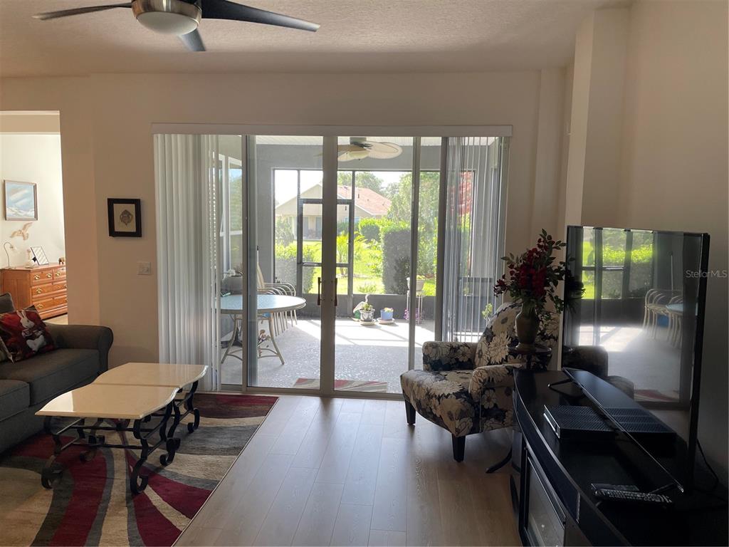 A living room features light wood flooring, a sliding glass door, and a screened-in patio — 108 CUPANIA COURT, GROVELAND, FL