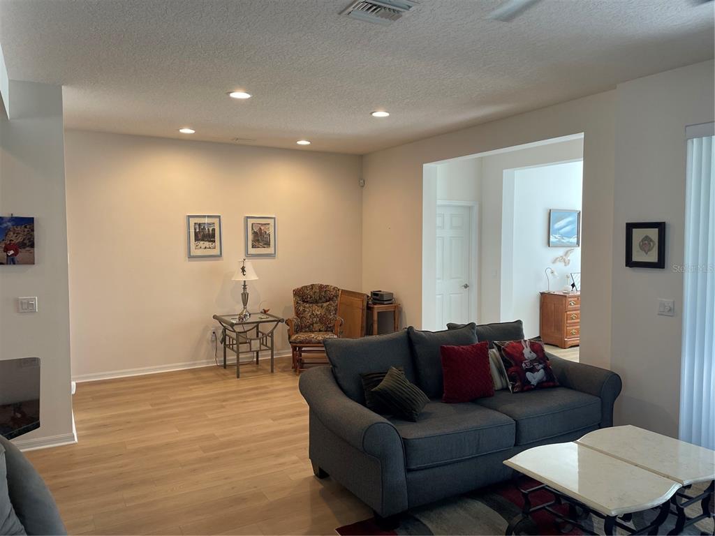 A living room features light wood flooring, a gray sofa, and a floral accent chair — 108 CUPANIA COURT, GROVELAND, FL