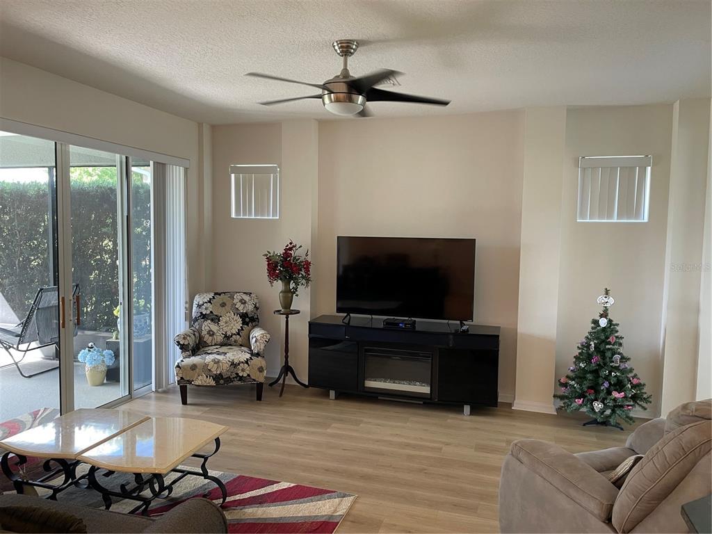 A living room features a television console, a patterned armchair, and a sliding glass door — 108 CUPANIA COURT, GROVELAND, FL
