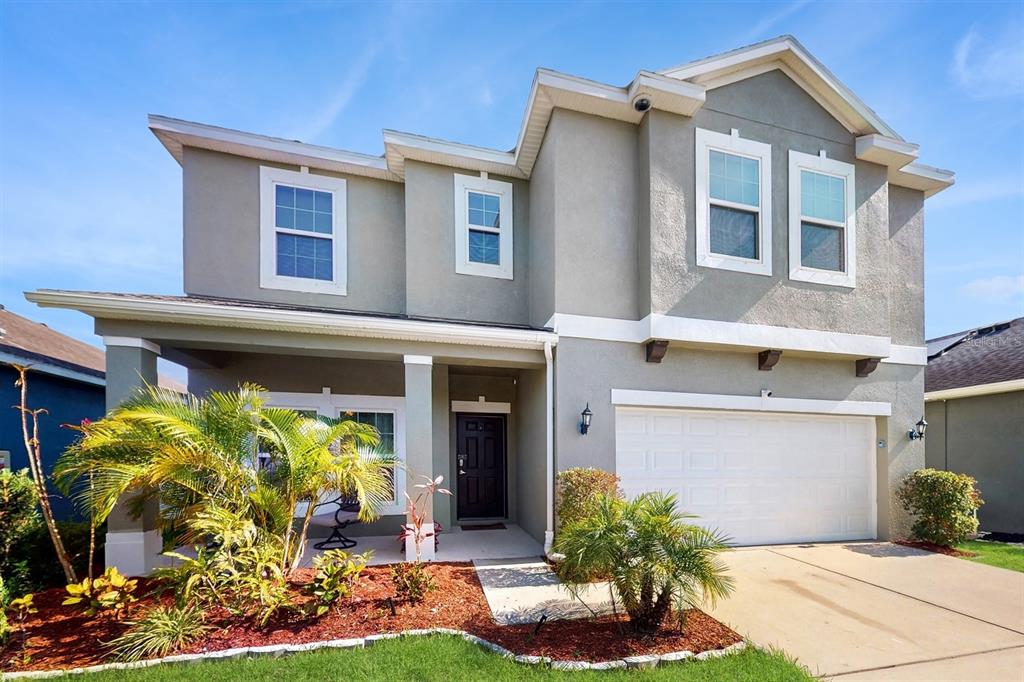 A two-story suburban house with a gray stucco exterior, a two-car garage, and landscaping — 8111 BRICKLETON WOODS AVENUE, GIBSONTON, FL