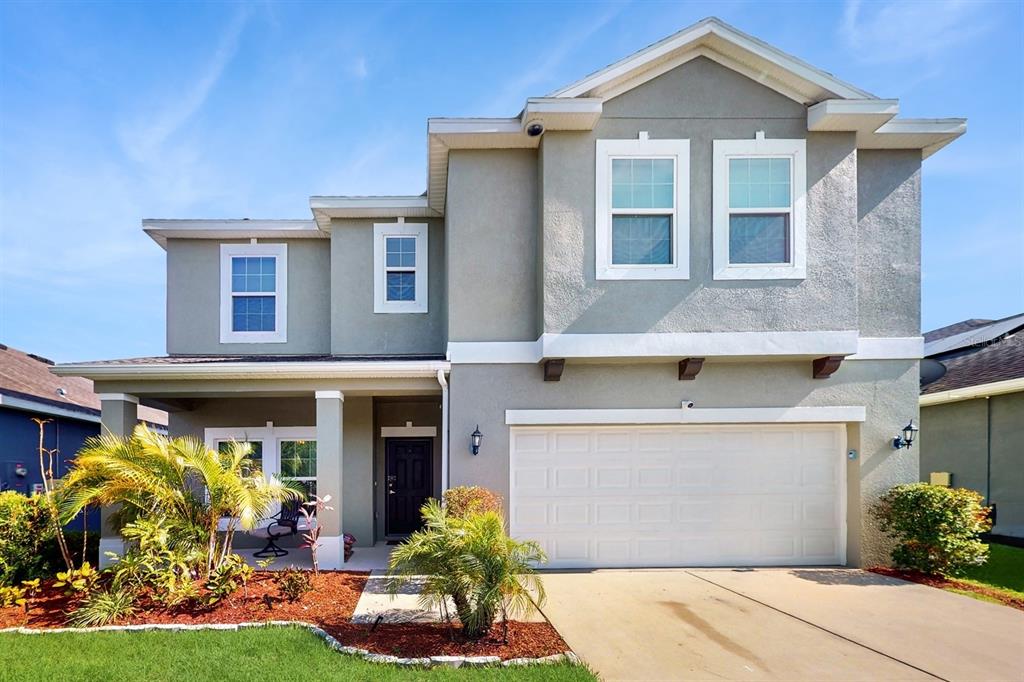 A two-story suburban house with a gray stucco exterior, a two-car garage, and a porch — 8111 BRICKLETON WOODS AVENUE, GIBSONTON, FL
