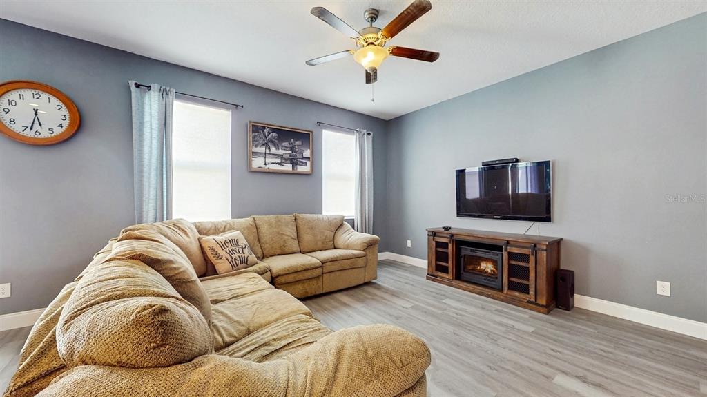 A living room features a tan sectional sofa, a television, and a fireplace media console — 8111 BRICKLETON WOODS AVENUE, GIBSONTON, FL