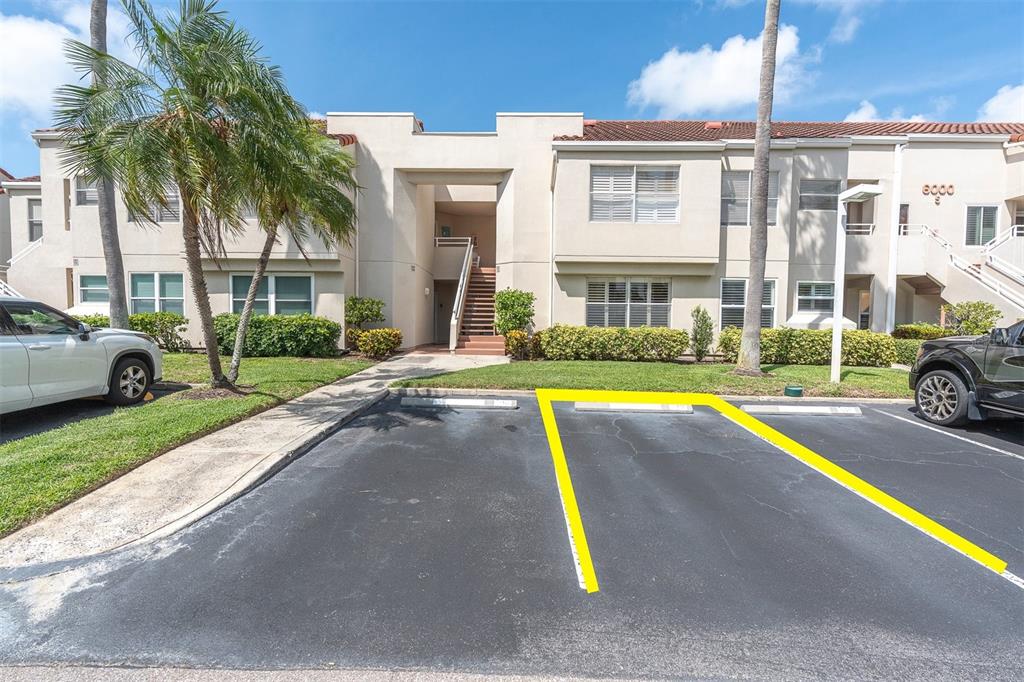 A two-story apartment building exterior features a parking lot with marked spaces and palm trees — 6000 BAHIA DEL MAR CIRCLE UNIT 131, ST PETERSBURG, FL