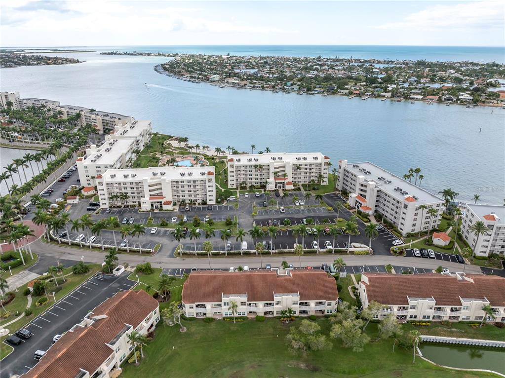 An aerial view shows several multi-story apartment buildings situated along a waterfront with parking lots — 6000 BAHIA DEL MAR CIRCLE UNIT 131, ST PETERSBURG, FL