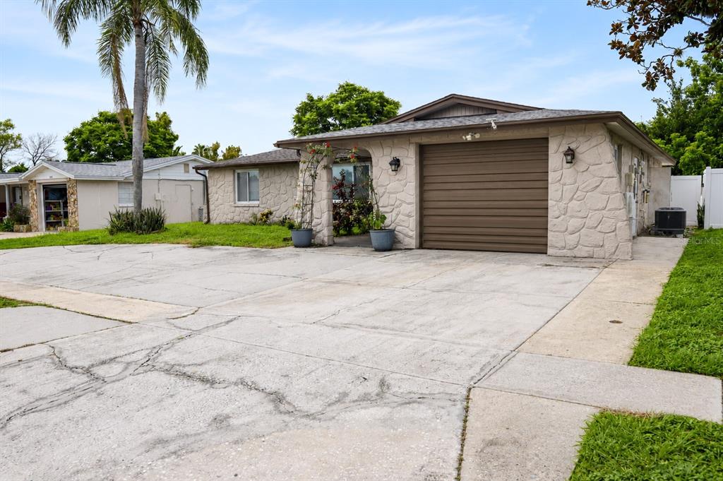 A single-story house with a stone facade, a brown garage door, and a concrete driveway — 6012 12TH AVENUE, NEW PORT RICHEY, FL