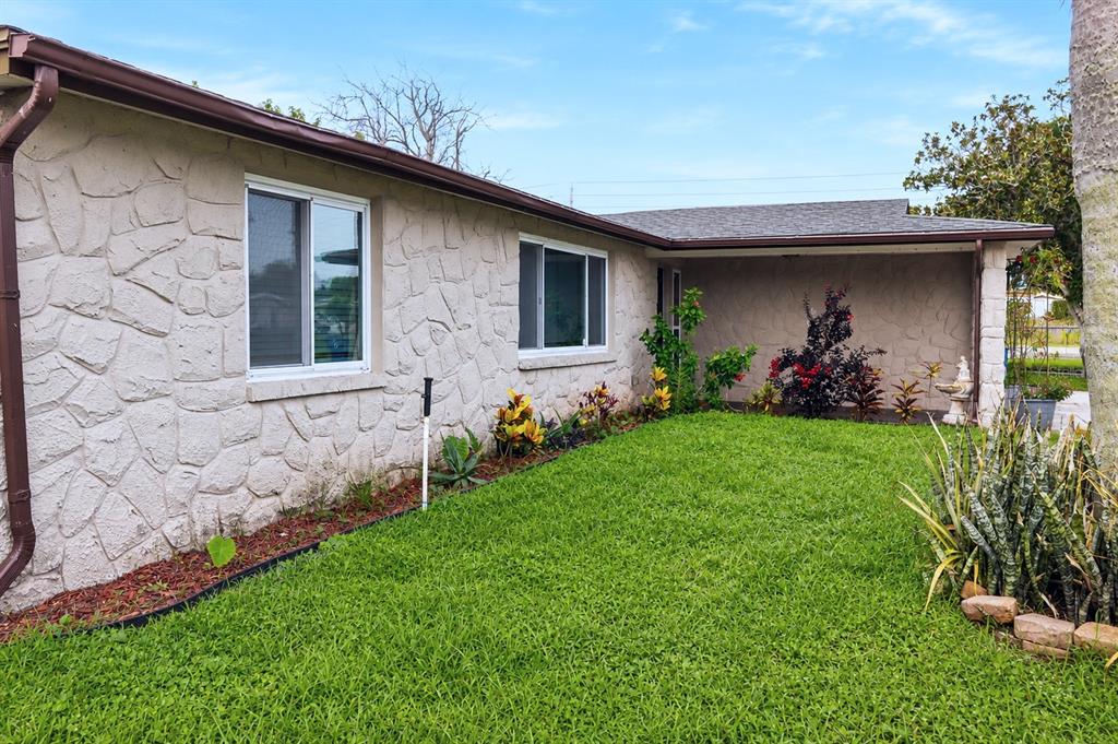 A single-story house with a stone-textured exterior, a covered entryway, and a green lawn — 6012 12TH AVENUE, NEW PORT RICHEY, FL