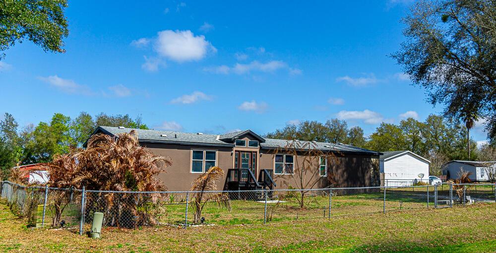 A brown manufactured home with a front porch sits behind a chain-link fence — 5472 Citrus Hill Drive, FL 33868, FL