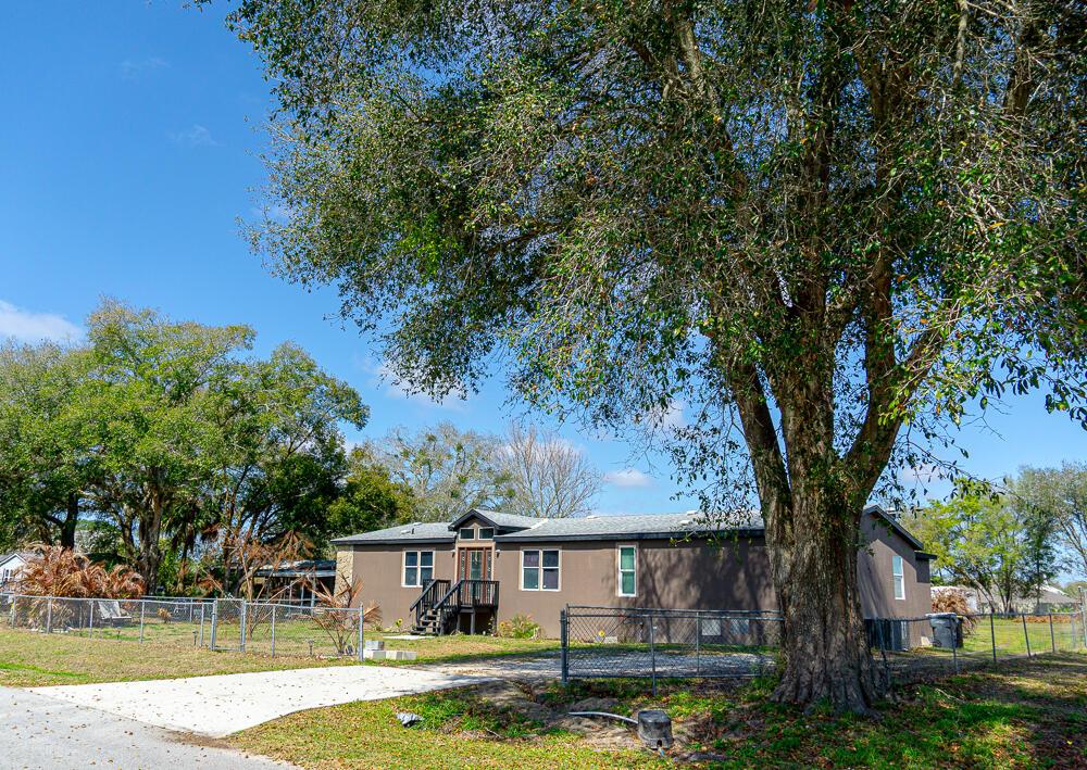 A single-story house with brown siding and a front porch sits behind a chain-link fence — 5472 Citrus Hill Drive, FL 33868, FL