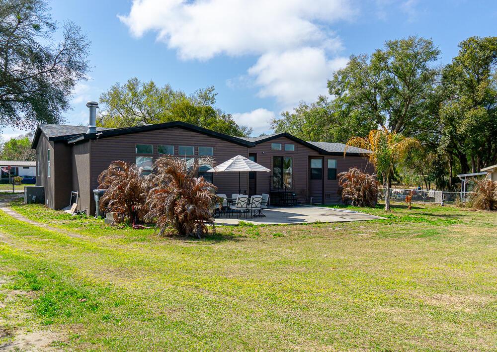 A brown single-story house with a patio, umbrella, and outdoor furniture in a grassy yard — 5472 Citrus Hill Drive, FL 33868, FL
