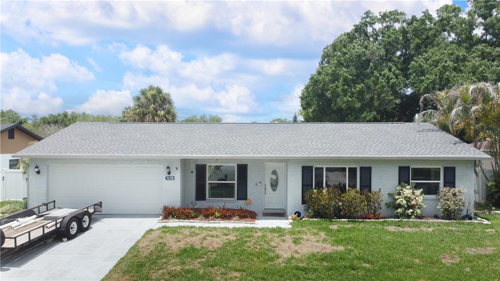 A single-story brick house with a gray shingled roof, white garage, and front landscaping — 4313 HOLLOW HILL DRIVE, TAMPA, FL