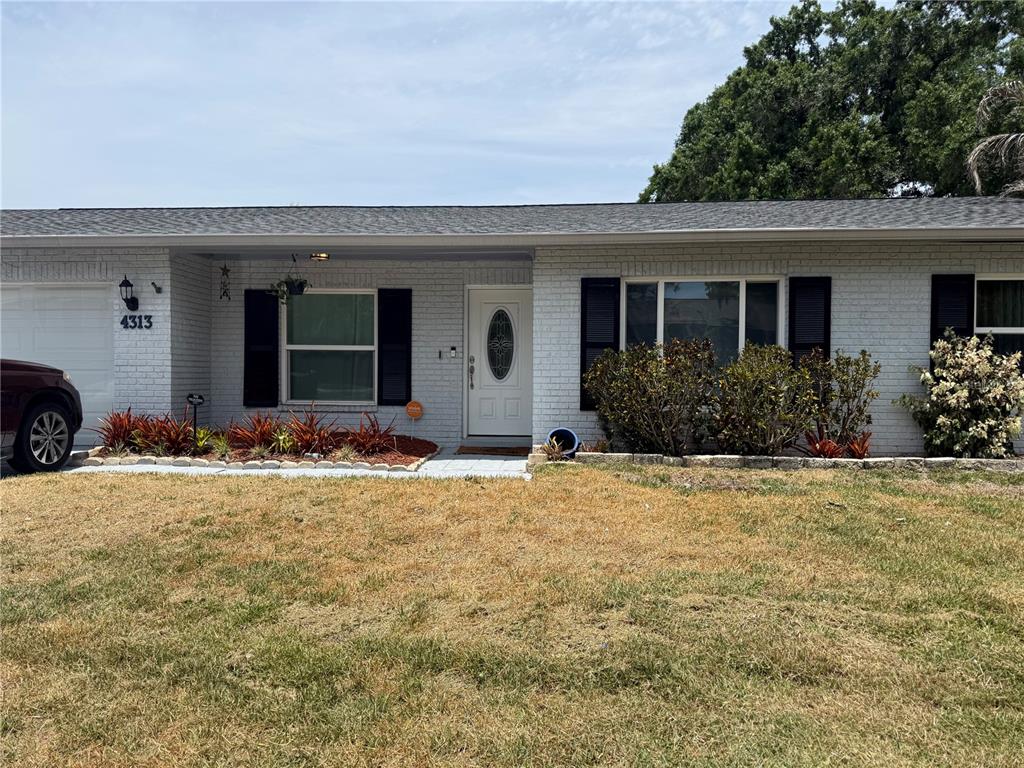 A single-story house with a white brick exterior, black shutters, and a dry lawn — 4313 HOLLOW HILL DRIVE, TAMPA, FL