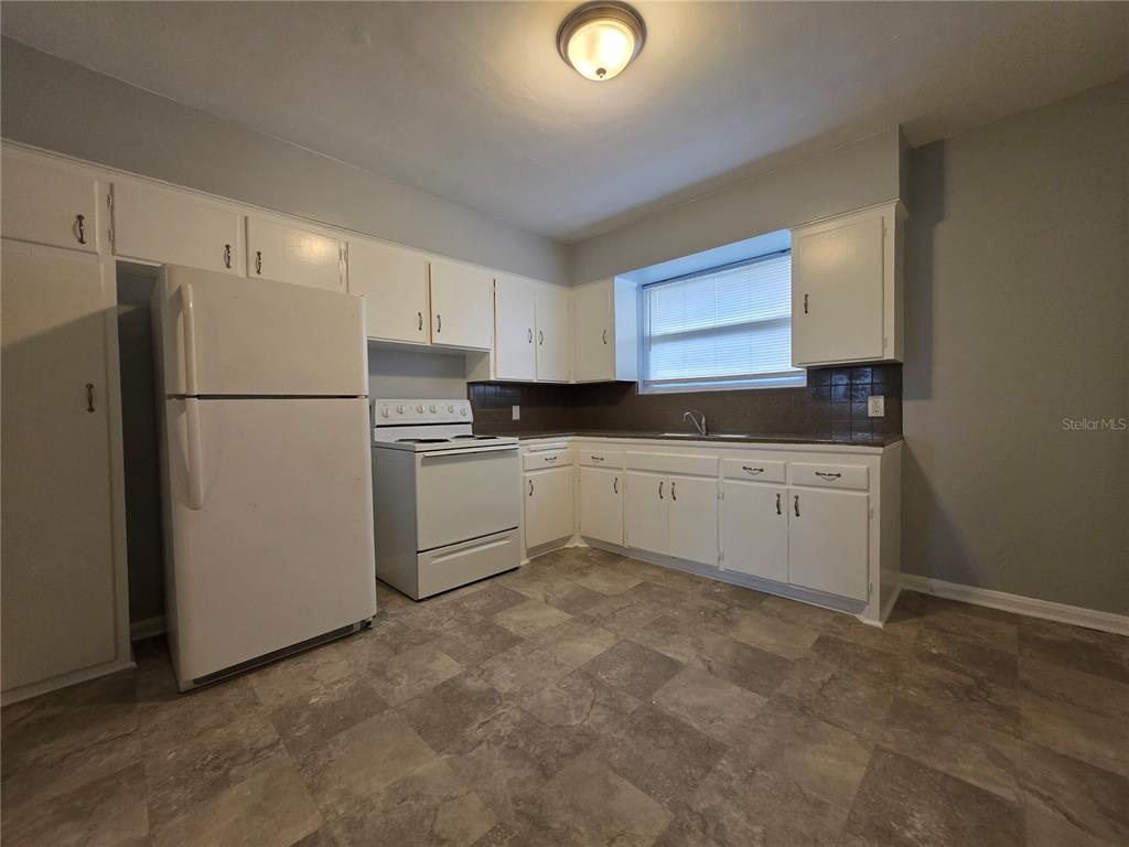 A kitchen features white cabinets, white appliances, a window, and gray patterned flooring — 3148 BELDEN STREET UNIT 3, JACKSONVILLE, FL