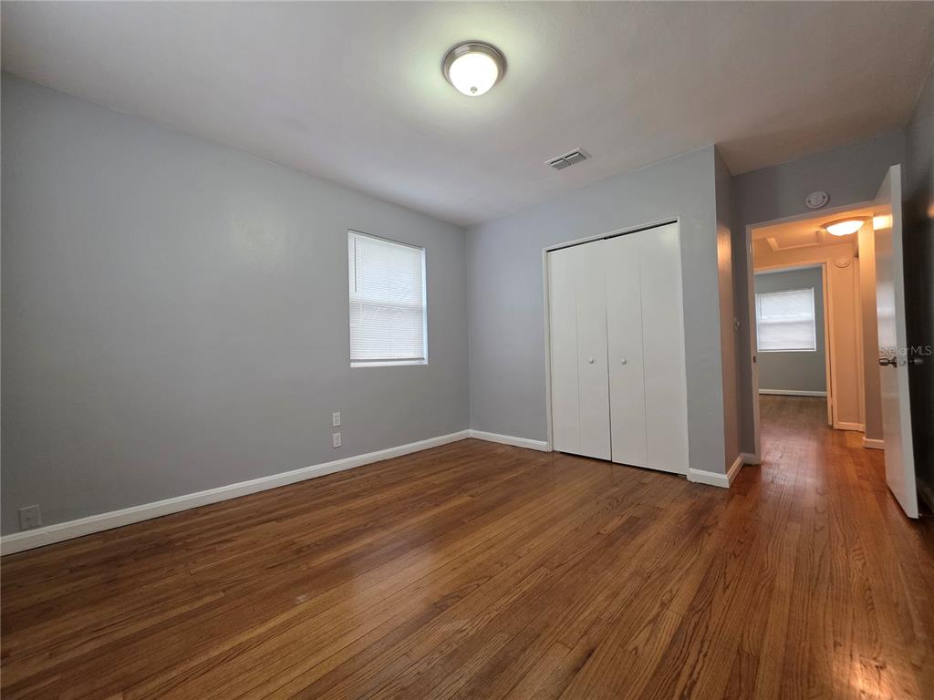 An empty bedroom features light gray walls, hardwood flooring, a window, and a white closet — 3148 BELDEN STREET UNIT 3, JACKSONVILLE, FL