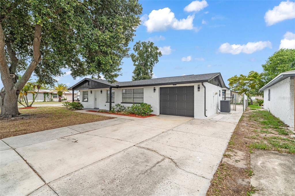 A single-story white brick house with a dark roof and a one-car garage — 3325 DARLINGTON ROAD, HOLIDAY, FL