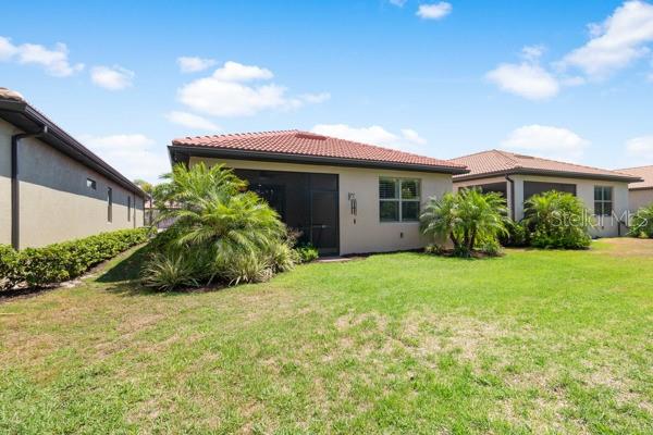 The exterior rear view of a house features a screened-in patio and landscaped palm trees — 200 SOLIERA STREET, NOKOMIS, FL