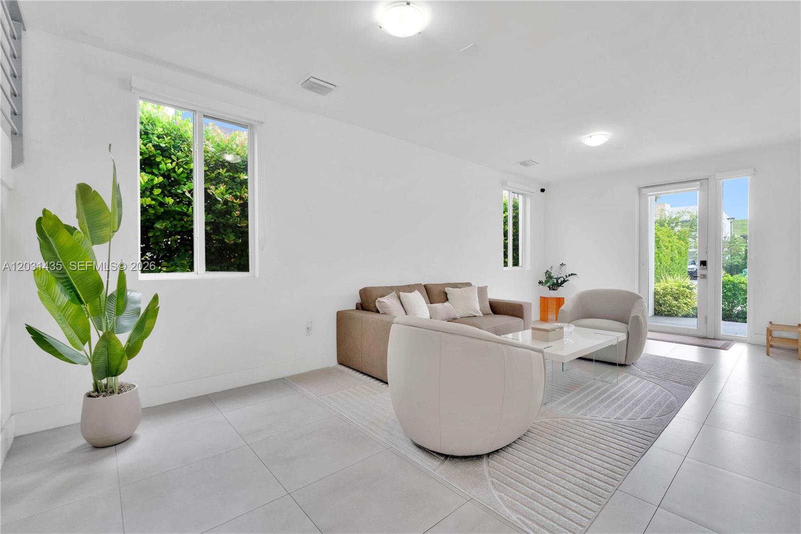 A bright living room features white walls, tile flooring, a sofa, and two armchairs — 6750 NW 103rd Ave, Doral FL 33178, DORAL, FL