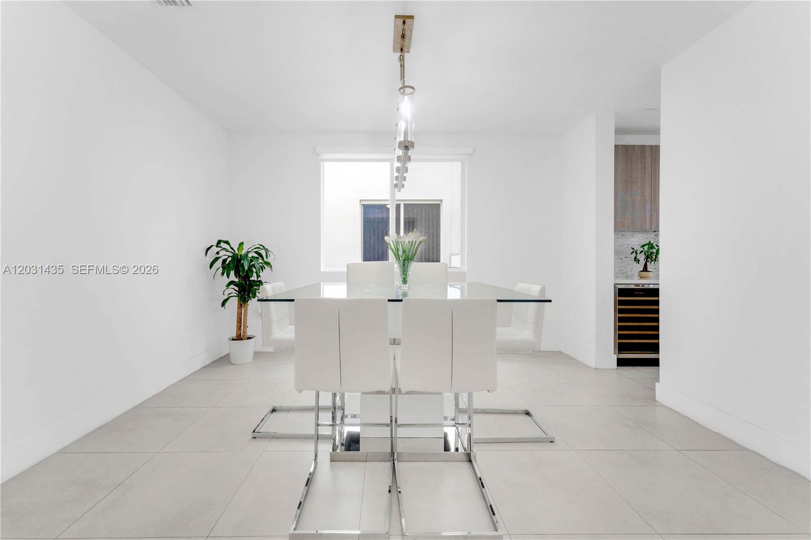 A modern dining room features a glass table, white chairs, and a linear pendant light — 6750 NW 103rd Ave, Doral FL 33178, DORAL, FL