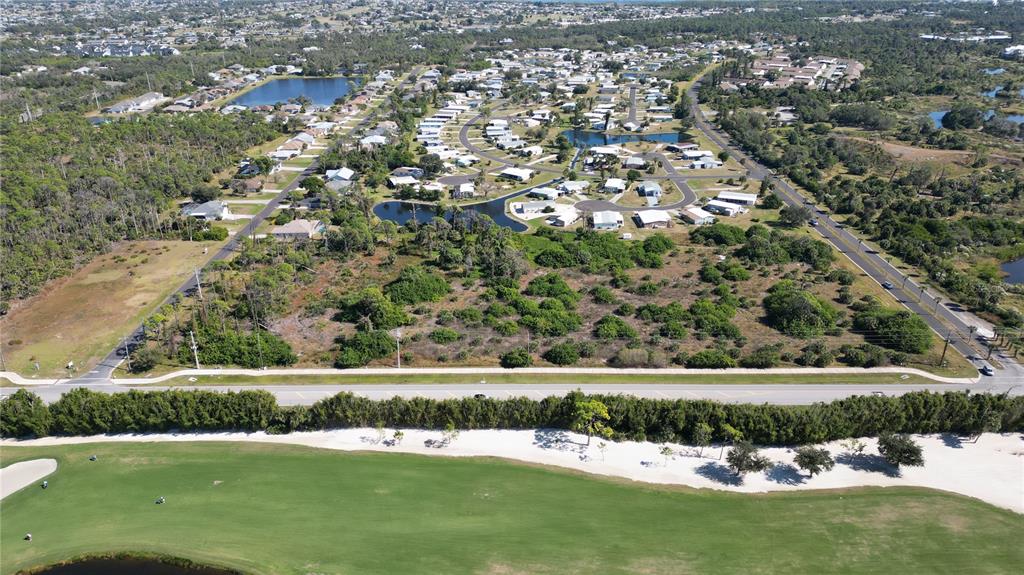 An aerial view shows a vacant lot bordered by a road, golf course, and neighborhood — 6601 PLACIDA ROAD, ENGLEWOOD, FL