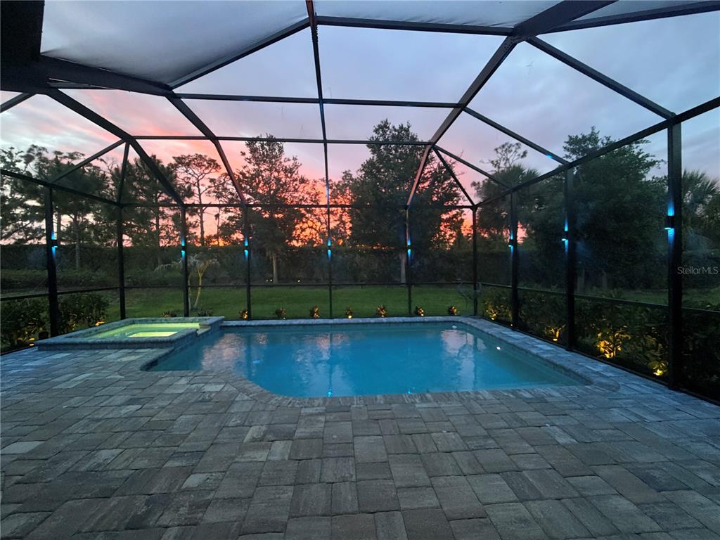 A screened-in pool and spa area with paver decking at sunset — 14659 DERNA TERRACE, BRADENTON, FL