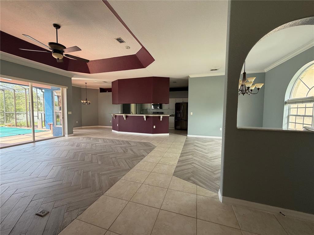 An open-concept living area features herringbone-patterned wood-look flooring, a large kitchen island, and pool access — 7061 OVENBIRD ROAD, WEEKI WACHEE, FL