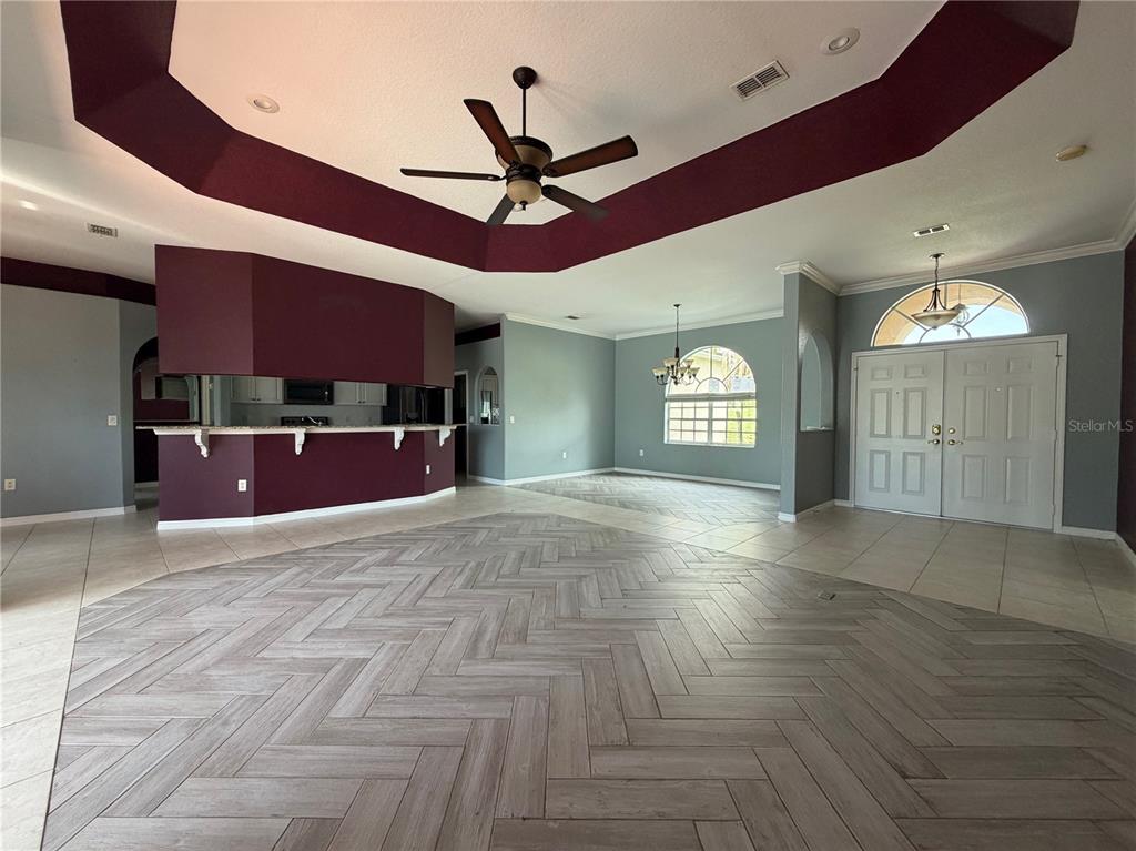 A spacious living area features a dark red tray ceiling, herringbone tile flooring, and an entryway — 7061 OVENBIRD ROAD, WEEKI WACHEE, FL