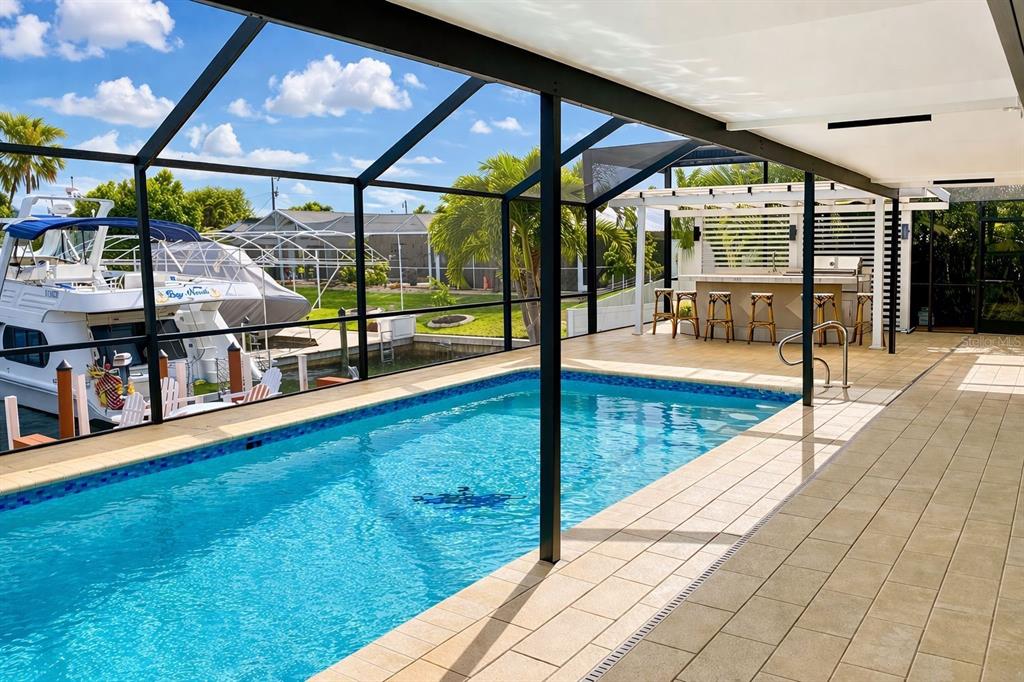A screened-in pool area features a tiled deck, an outdoor bar, and a boat dock — 808 SW 52ND STREET, CAPE CORAL, FL