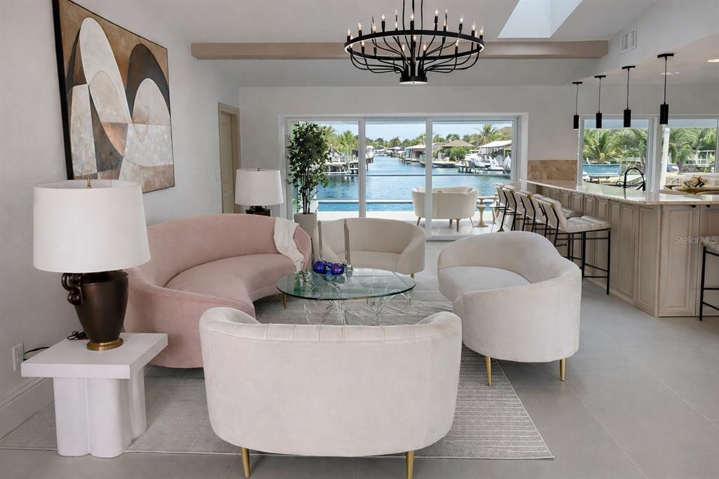 A living room with curved furniture, a chandelier, and a view of a boat canal — 808 SW 52ND STREET, CAPE CORAL, FL