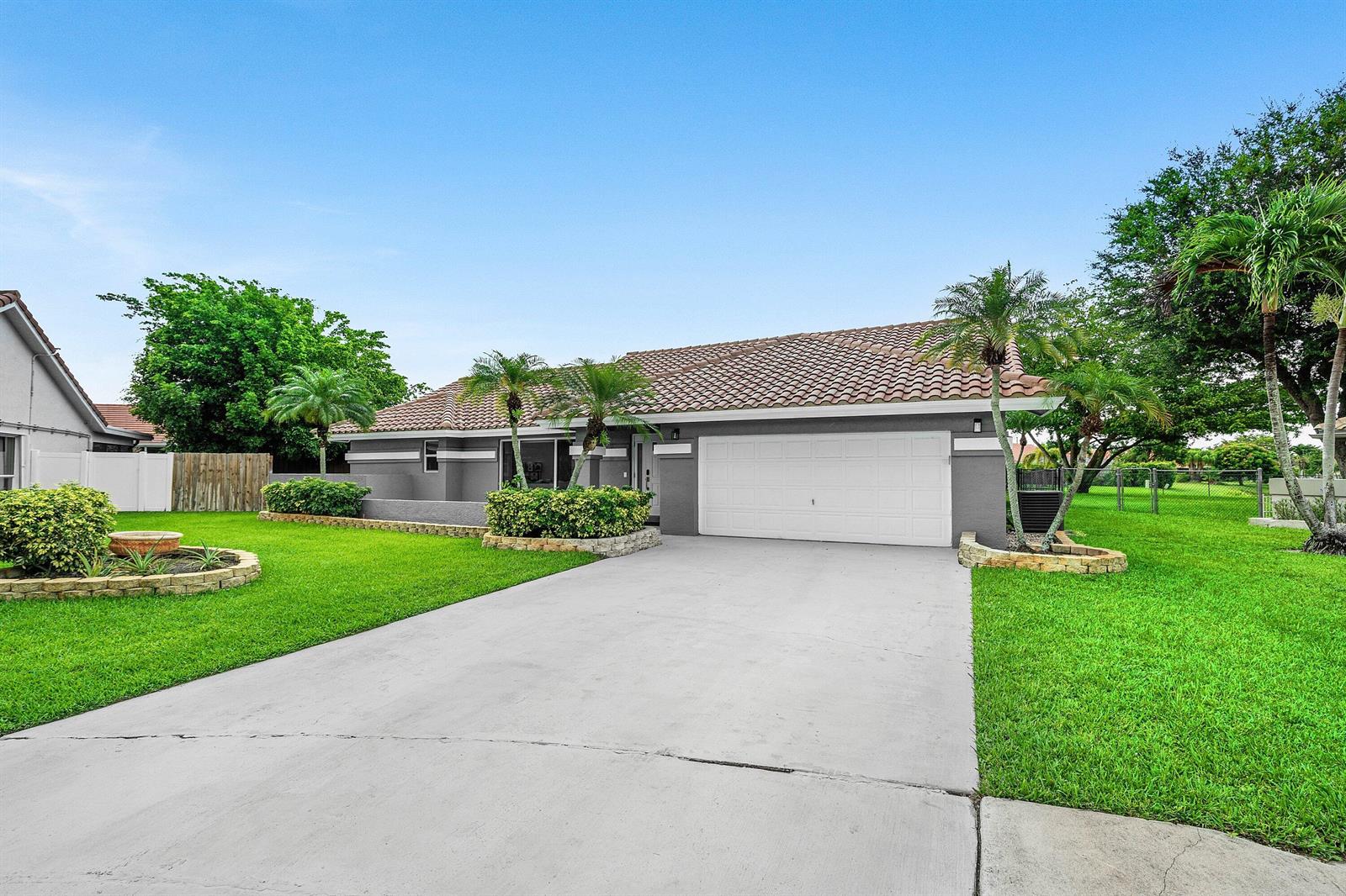 A single-story gray house with a white garage door, tile roof, and landscaped front yard — 5781 Laurel Green Circle, Boynton Beach FL 33437, BOYNTON BEACH, FL