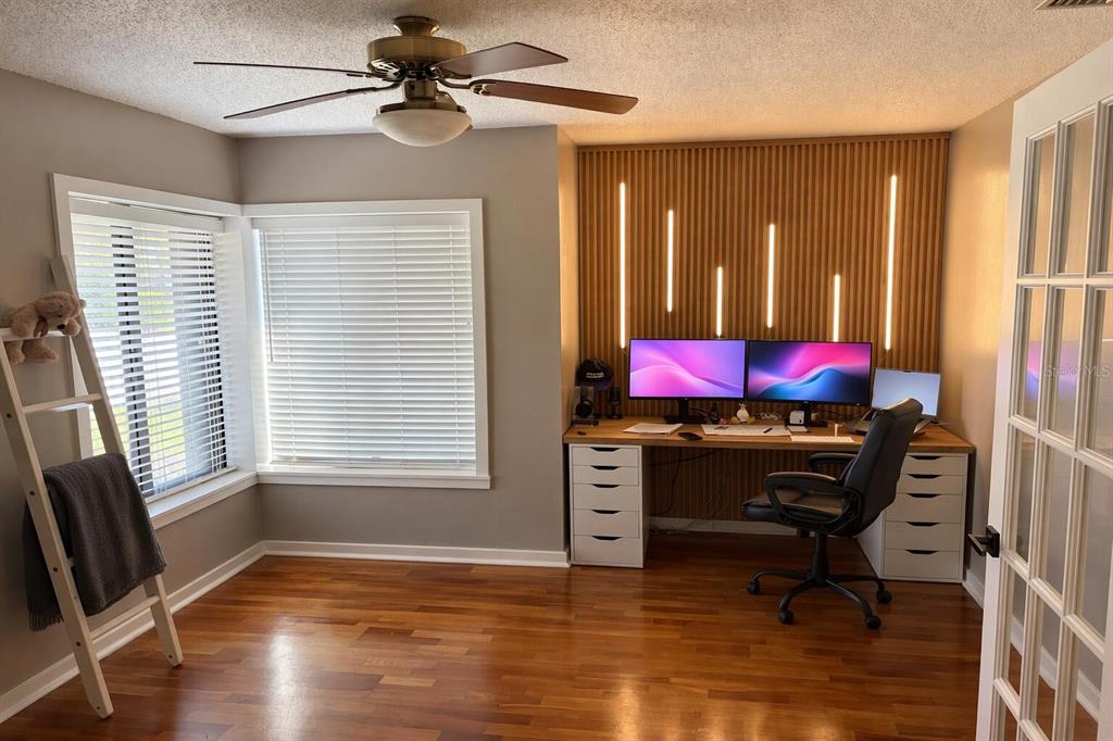 A home office featuring a wood-slat accent wall with integrated lighting and a dual-monitor desk — 249 WATERFORD COURT, ALTAMONTE SPRINGS, FL