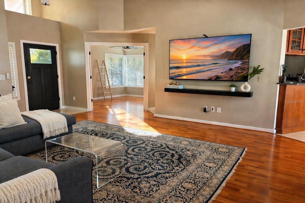 A living room features hardwood floors, a large area rug, and a wall-mounted television — 249 WATERFORD COURT, ALTAMONTE SPRINGS, FL