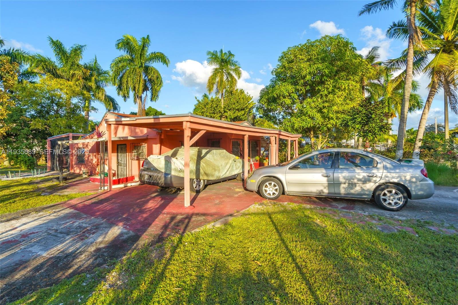 A single-story house with a carport and two parked cars sits on a grassy lot — 191 NW 83rd St, Miami FL 33150, MIAMI, FL